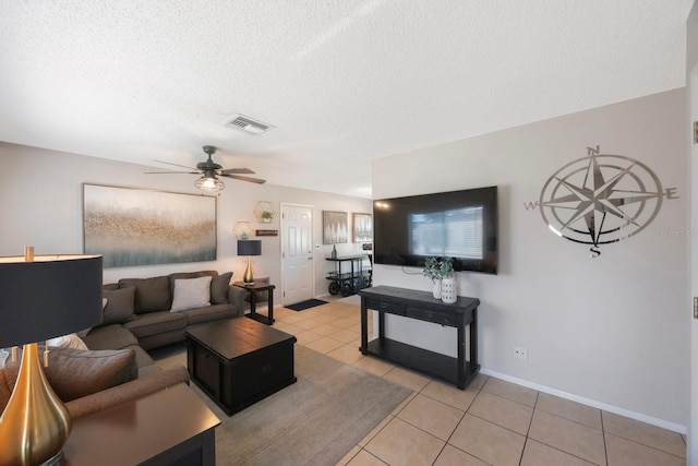 tiled living room with ceiling fan and a textured ceiling