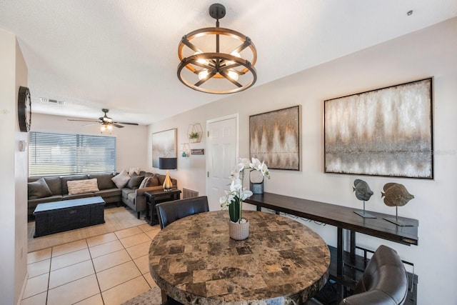 tiled dining room featuring a textured ceiling and ceiling fan with notable chandelier