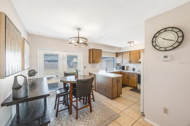 kitchen with pendant lighting, a textured ceiling, an inviting chandelier, and plenty of natural light