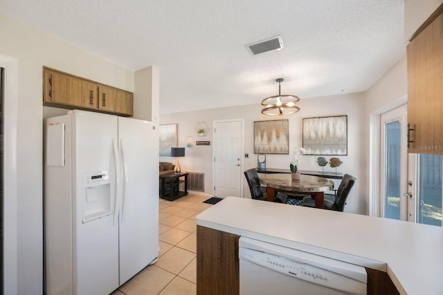 kitchen with pendant lighting, white appliances, an inviting chandelier, light tile patterned floors, and a textured ceiling