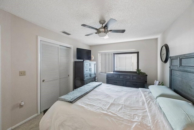 carpeted bedroom featuring a textured ceiling, a closet, and ceiling fan