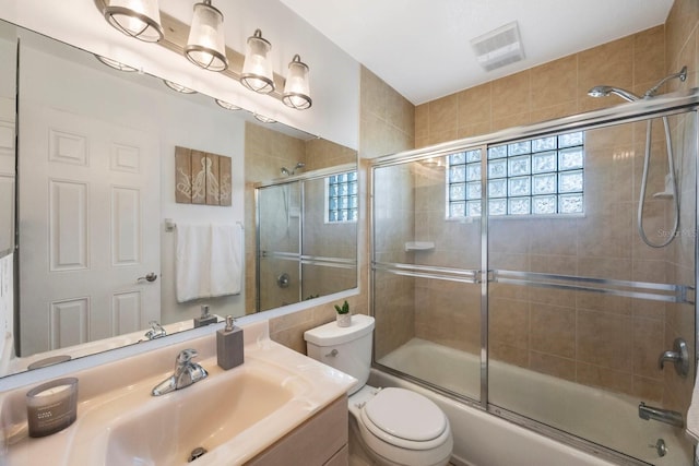 full bathroom featuring vanity, toilet, and bath / shower combo with glass door