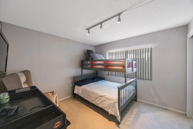 carpeted bedroom featuring a textured ceiling and rail lighting