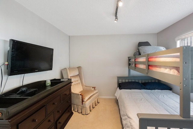 bedroom with a textured ceiling, light carpet, and track lighting