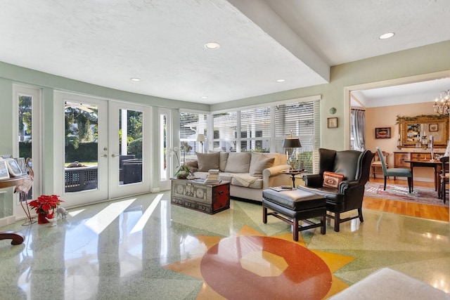 living room featuring french doors, a chandelier, a textured ceiling, and light wood-type flooring