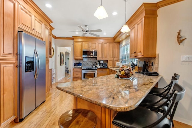 kitchen featuring a breakfast bar, light stone countertops, light hardwood / wood-style floors, kitchen peninsula, and stainless steel appliances