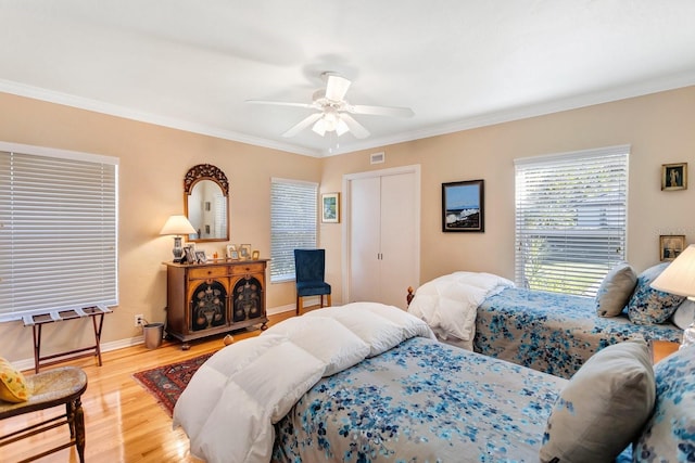 bedroom with hardwood / wood-style flooring, ceiling fan, ornamental molding, and a closet