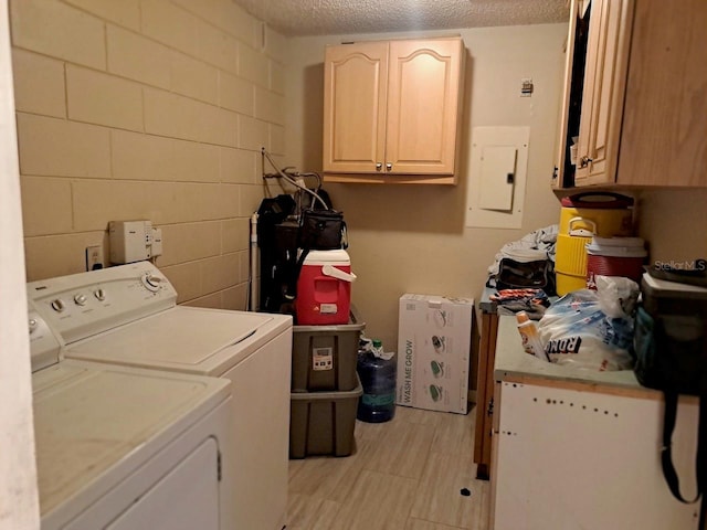 washroom featuring cabinets, a textured ceiling, electric panel, and washing machine and clothes dryer