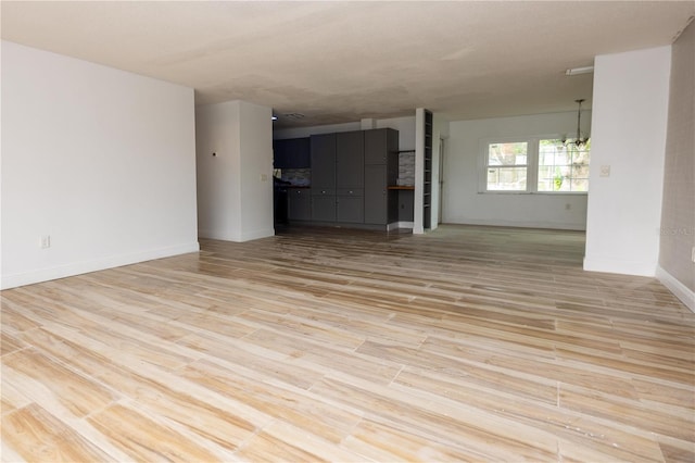 unfurnished living room with light hardwood / wood-style flooring and a chandelier