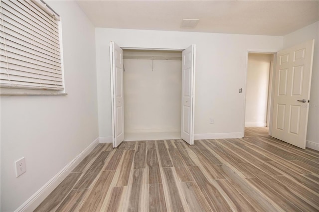 unfurnished bedroom with wood-type flooring and a closet