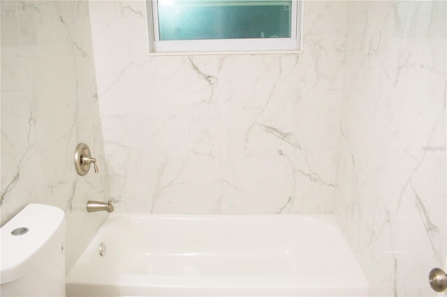 bathroom featuring tiled shower / bath combo and toilet