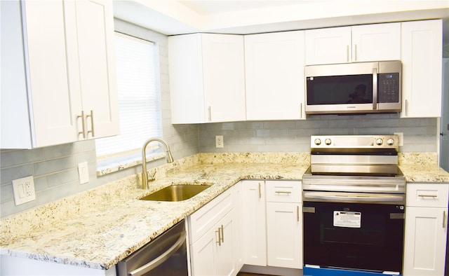 kitchen featuring light stone countertops, white cabinetry, sink, and appliances with stainless steel finishes