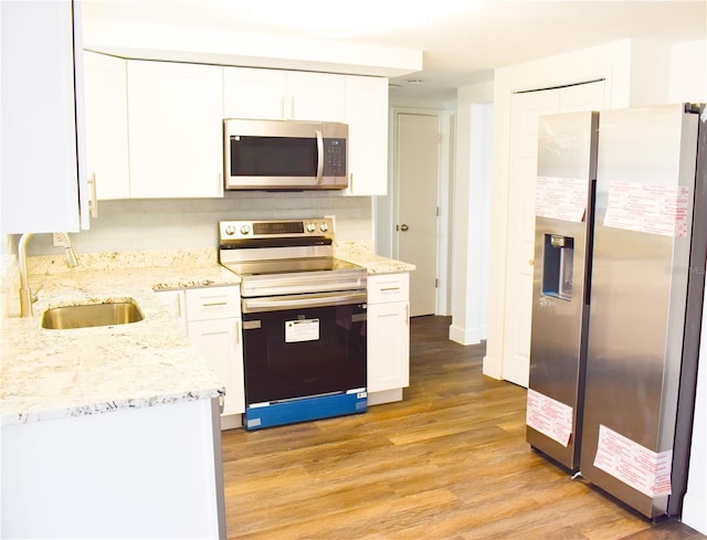 kitchen featuring white cabinets, decorative backsplash, light wood-type flooring, and stainless steel appliances