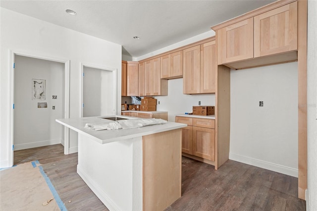 kitchen with dark hardwood / wood-style floors, a kitchen island with sink, and light brown cabinets