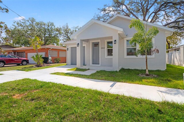 bungalow-style house featuring stucco siding, concrete driveway, a garage, and a front yard