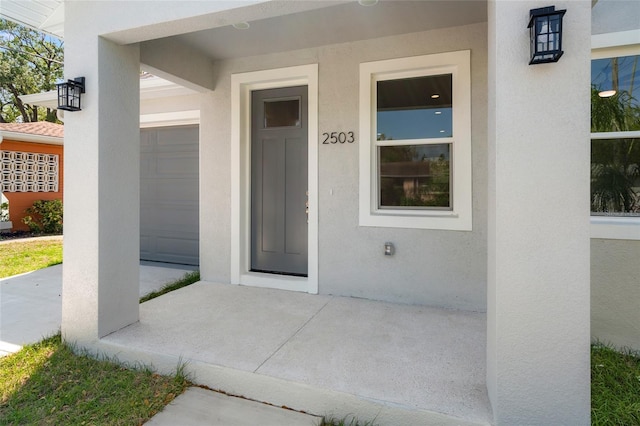 property entrance featuring a garage and stucco siding