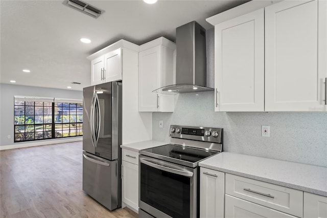 kitchen featuring wall chimney range hood, white cabinetry, tasteful backsplash, visible vents, and stainless steel appliances