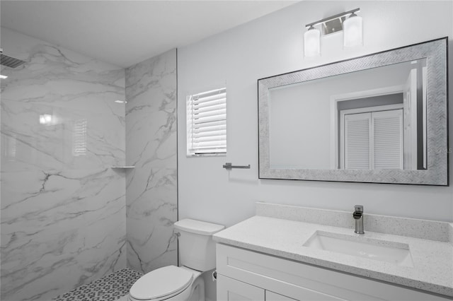 bathroom with toilet, a marble finish shower, and vanity