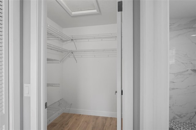 walk in closet with wood finished floors