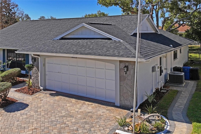 view of property exterior featuring stone siding, cooling unit, a shingled roof, and a garage