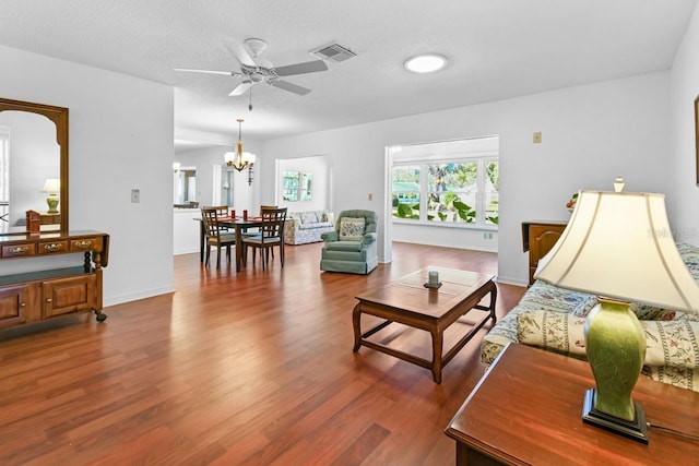 living room featuring ceiling fan with notable chandelier, a textured ceiling, and hardwood / wood-style flooring