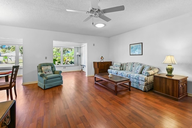 living room featuring hardwood / wood-style flooring, ceiling fan, and a textured ceiling