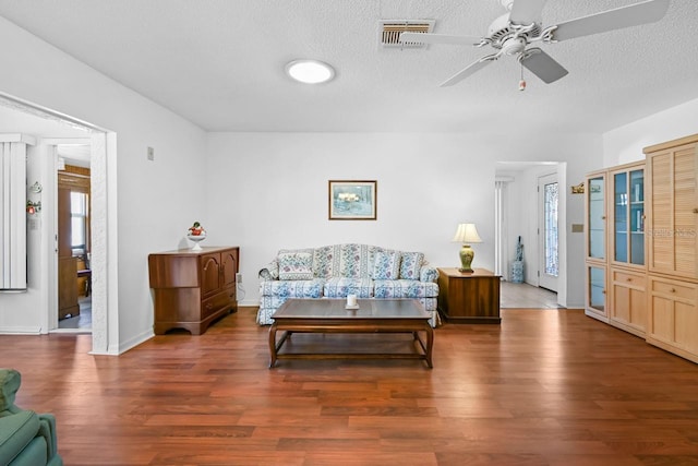 living room featuring a textured ceiling, dark hardwood / wood-style flooring, and ceiling fan