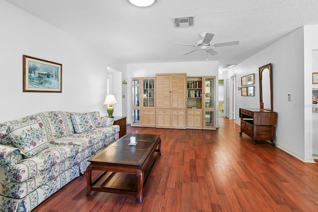 living room with ceiling fan, dark hardwood / wood-style flooring, and a textured ceiling