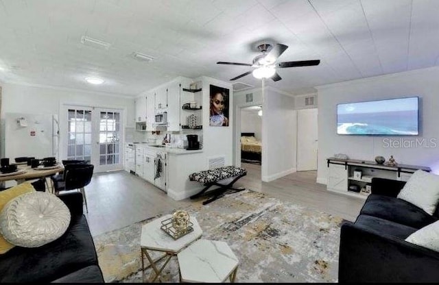 living room with light wood-type flooring, ceiling fan, crown molding, and sink