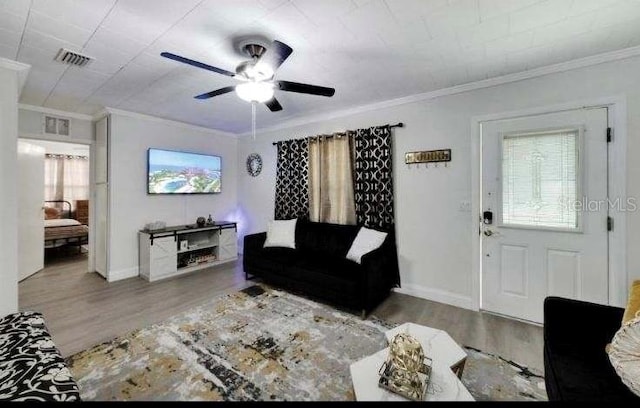 living room with hardwood / wood-style flooring, ceiling fan, and crown molding