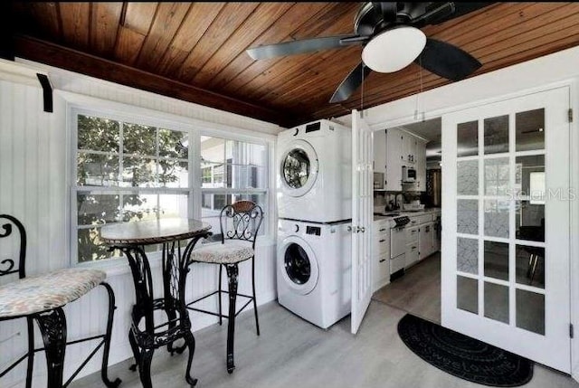 laundry room with ceiling fan, stacked washer and clothes dryer, wood ceiling, and light hardwood / wood-style floors