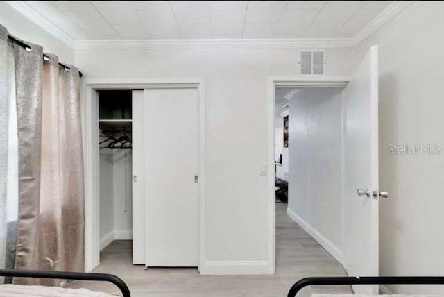 bedroom with a closet, ornamental molding, and light wood-type flooring