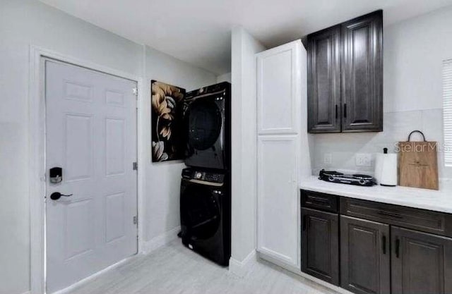 washroom featuring stacked washer / drying machine and light hardwood / wood-style flooring