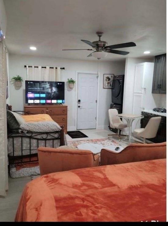 living room with stacked washer / dryer and ceiling fan