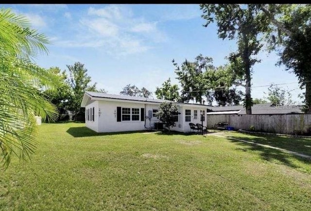 rear view of house with central AC and a yard