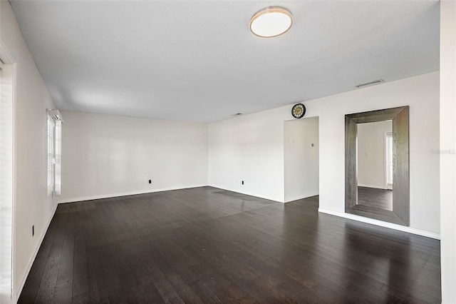 unfurnished room featuring dark wood-type flooring and a wealth of natural light