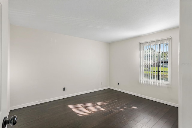 empty room with a textured ceiling and dark hardwood / wood-style floors