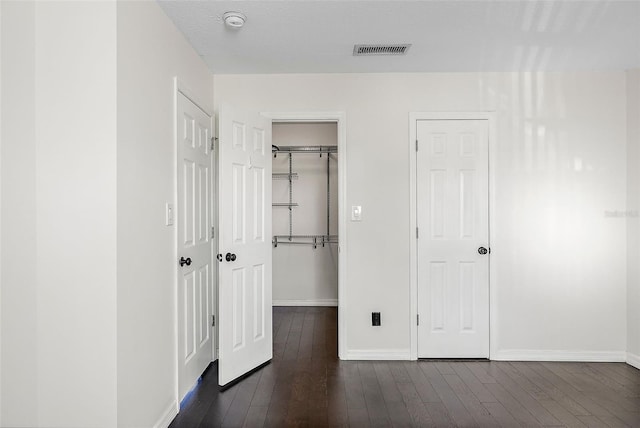 unfurnished bedroom with a textured ceiling and dark wood-type flooring