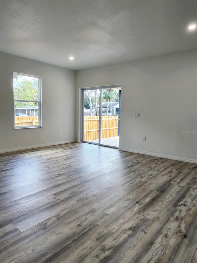 spare room featuring recessed lighting, wood finished floors, and baseboards