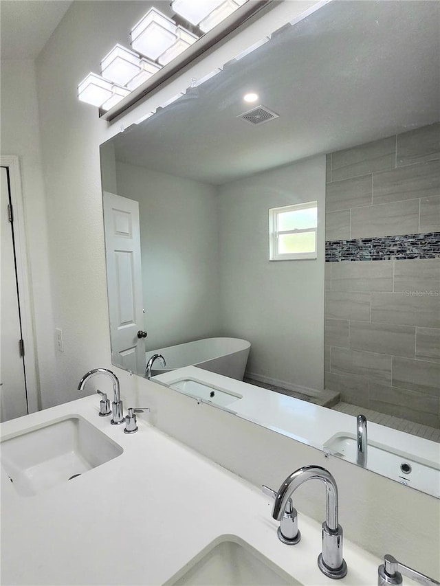 full bath with a freestanding tub, visible vents, and a sink