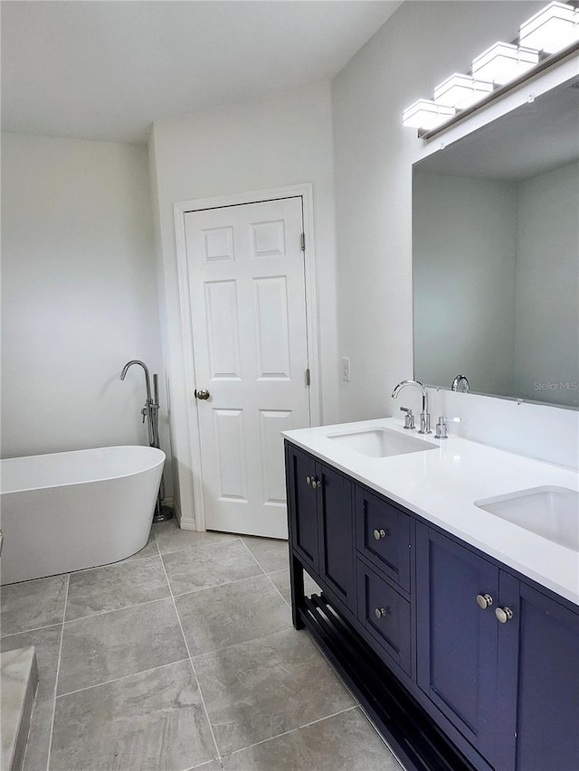 full bath featuring a sink, a freestanding bath, and double vanity