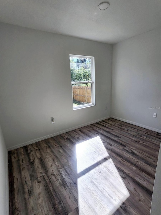 unfurnished room with dark wood-style floors and baseboards