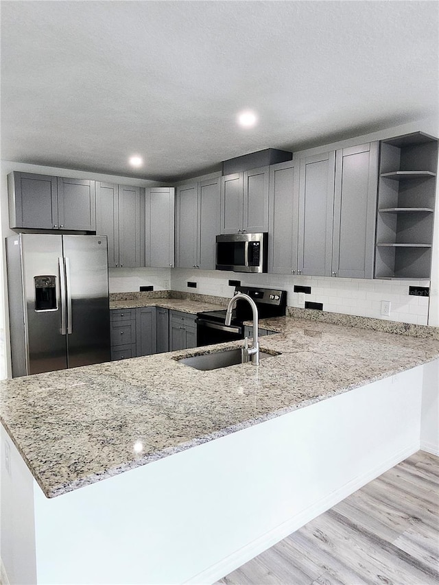 5714 Olive Dr, New Port Richey, FL 34652 - kitchen with appliances with stainless steel finishes, light stone counters, a peninsula, gray cabinets, and open shelves