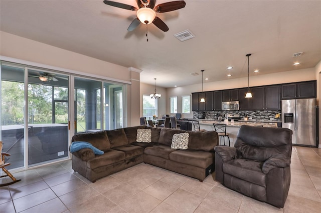 tiled living room featuring ceiling fan with notable chandelier