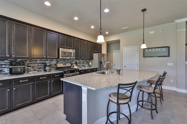 kitchen with appliances with stainless steel finishes, a center island with sink, decorative light fixtures, and sink