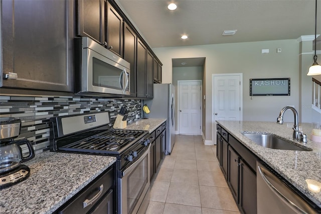 kitchen with light stone countertops, appliances with stainless steel finishes, decorative backsplash, sink, and pendant lighting