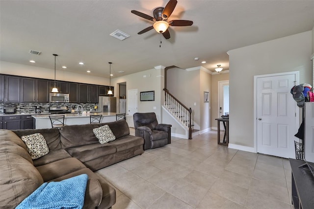 living room with ceiling fan, crown molding, and light tile patterned floors