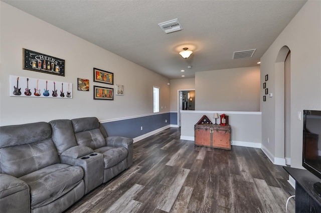 living room with a textured ceiling and dark hardwood / wood-style floors