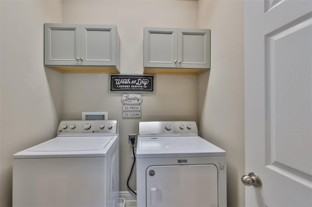 laundry room with washing machine and clothes dryer and cabinets