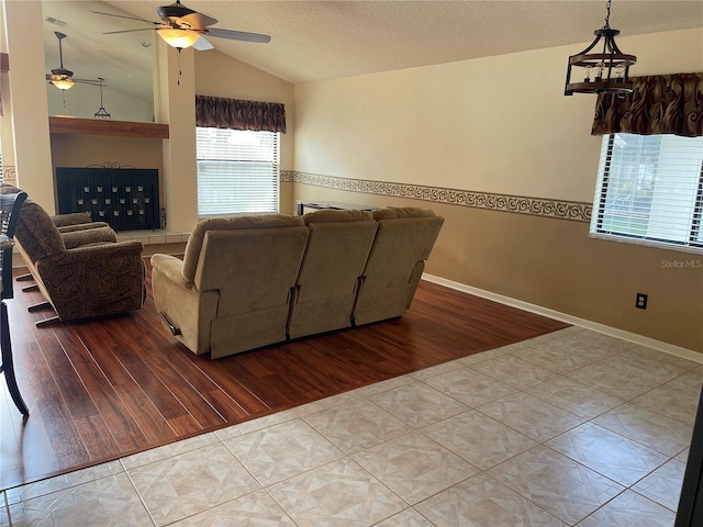 living room featuring ceiling fan, vaulted ceiling, a textured ceiling, and light tile patterned flooring